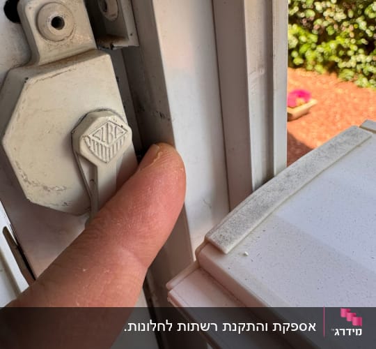 אצבע מחזיקה מנגנון פתיחה של תריס לבן